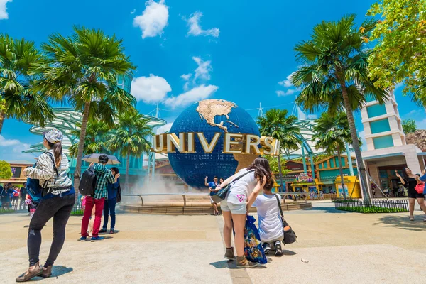 Tourists and theme park visitors taking pictures of the large rotating globe fountain in front of Universal Studios — Stock Photo, Image