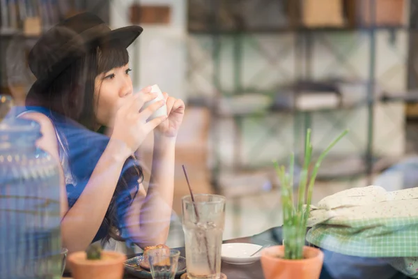 Молодая азиатка пьет кофе через зеркало — стоковое фото