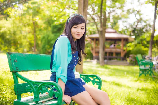Привлекательная молодая азиатка, сидящая на скамейке — стоковое фото