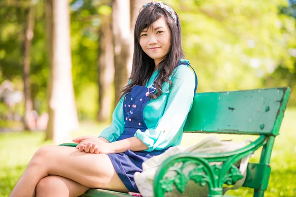 年轻漂亮的亚洲女人坐在长椅上 — 图库照片