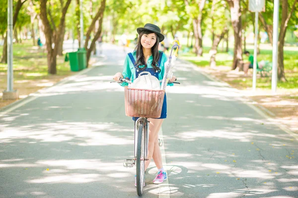 Asiática jovem mulher com uma bicicleta em um parque de verão . — Fotografia de Stock