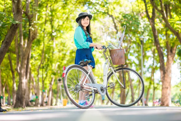 Aziatische jonge vrouw met een fiets in een zomer park. — Stockfoto