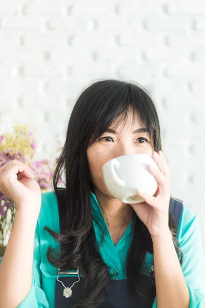 Όμορφη νεαρή γυναίκα της Ασίας με ένα φλιτζάνι τσάι σε ένα καφενείο — Φωτογραφία Αρχείου