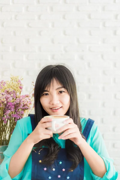 Linda jovem mulher asiática com uma xícara de chá em um café — Fotografia de Stock