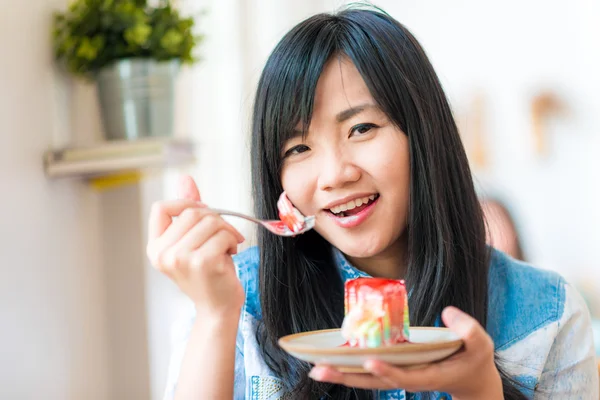 Retrato de joven asiático bastante sonriente mujer comiendo pastel en la cafetería — Foto de Stock