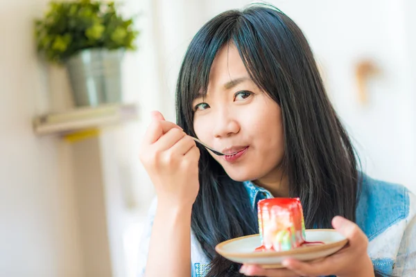 在咖啡厅吃蛋糕的年轻亚洲相当微笑女人的画像 — 图库照片