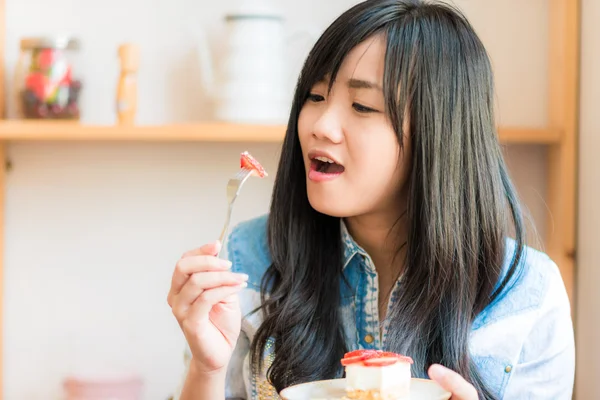 微笑亚洲女人在面包店咖啡馆吃一些草莓蛋糕 — 图库照片