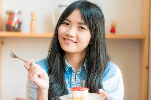 在咖啡厅吃蛋糕的年轻亚洲相当微笑女人的画像 — 图库照片