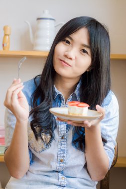 Güzel gülümseyen genç kadın Çilekli pasta fırın s ısırma