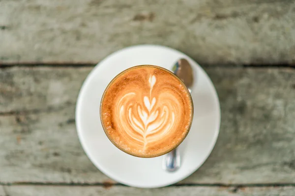 Kopi latte seni dengan pola daun pada latar belakang kayu — Stok Foto