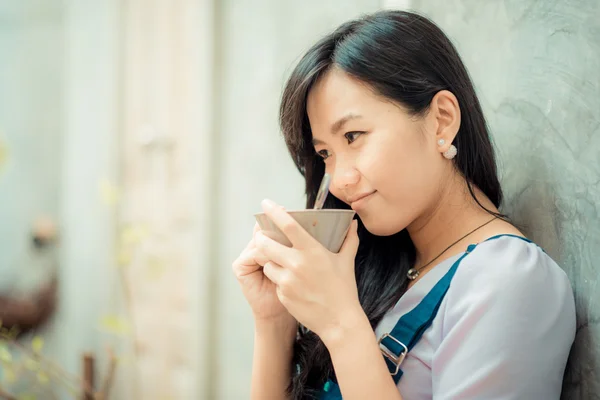 Mooie Aziatische jonge vrouw met een koffiekopje op zoek naar camera op — Stockfoto