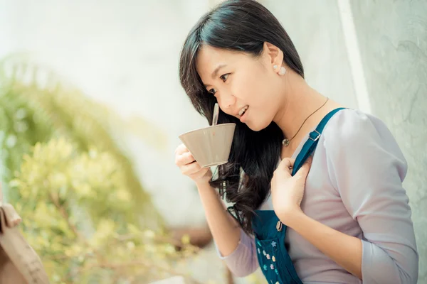 Beautiful asian young woman with coffee cup looking to camera at — Stock Photo, Image