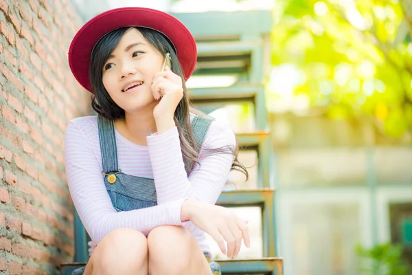 Young asian hipster woman sitting and talking on phone — Stock Photo, Image