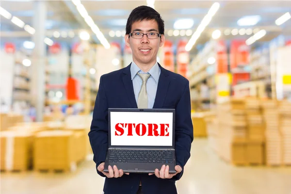 Business man holding digital laptop computer showing store word