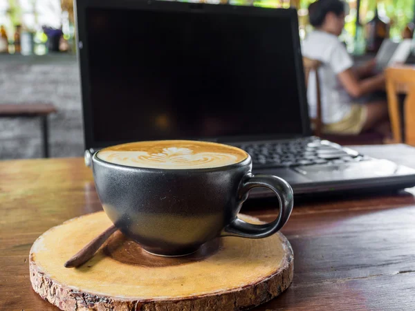 Laptop i filiżankę kawy na starym drewnianym stole — Zdjęcie stockowe