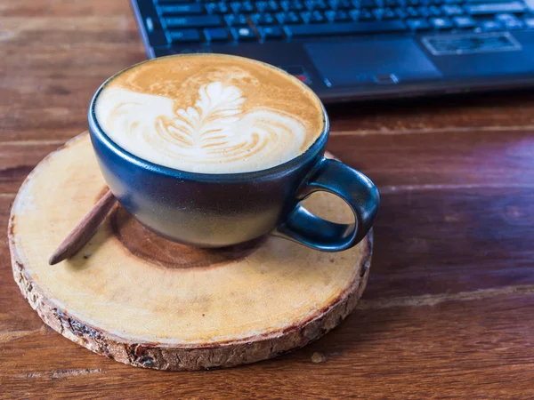 Laptop with latte art coffee cup on old wooden table — Stock Photo, Image