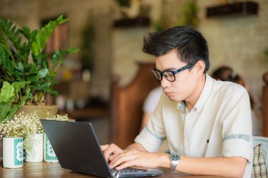 Kafede tablet bilgisayar kullanan genç Asyalı öğrenci adam