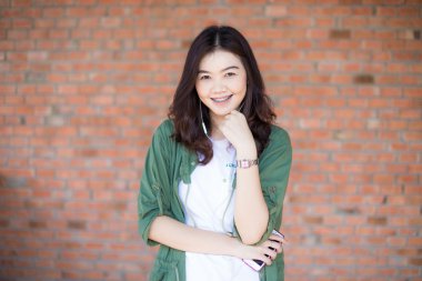 Mutlu Asyalı kadın siyah saçlı karşı eski tuğla Wal ayakta