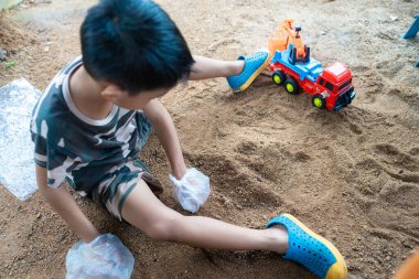Küçük okul çocuğu evde kumların üzerinde oyuncak oynuyor. Doğayı öğrenen çocuklar.