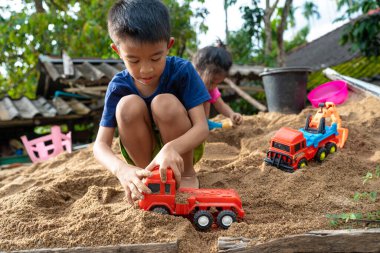 Küçük okul çocuğu evde kumların üzerinde oyuncak oynuyor. Doğayı öğrenen çocuklar.