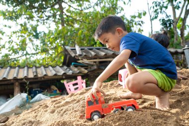 Küçük okul çocuğu evde kumların üzerinde oyuncak oynuyor. Doğayı öğrenen çocuklar.