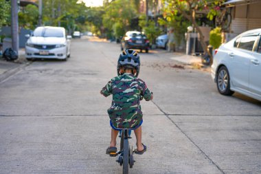 Asyalı okul çocuğu şehir merkezindeki köyde bisiklet sürmekten zevk alıyor.
