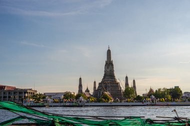 Gün batımında Wat Arun Tapınağı geleneksel seyahat teknesiyle Bangkok, Tayland nehrinde