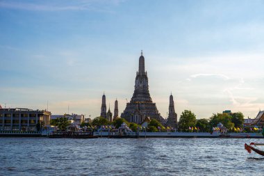 Gün batımında Wat Arun Tapınağı geleneksel seyahat teknesiyle Bangkok, Tayland nehrinde