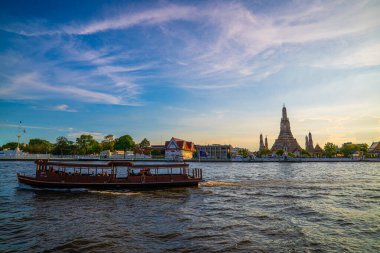Gün batımında Wat Arun Tapınağı geleneksel seyahat teknesiyle Bangkok, Tayland nehrinde
