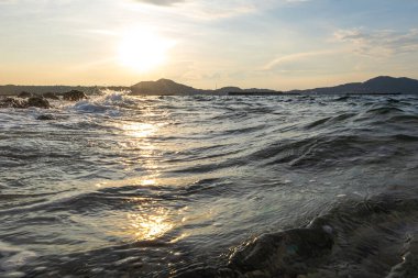Deniz sahili dalgası günbatımı su sıçratıyor.