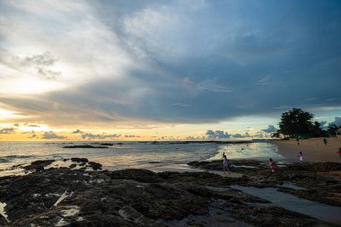 Sahilde gün batımının silueti. İnsanlar yaz tatilinin tadını çıkarıyorlar.