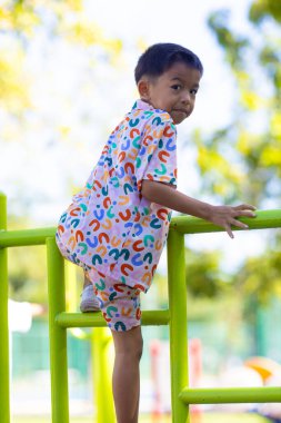 Küçük Asyalı çocuk şehir parkında oyun parkında oyuncakçılık yaparken eğleniyor.