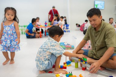 Baba sevimli anaokulu çocuğu ve kız çocuğuyla renkli oyuncak bloğu binasında oynuyor.