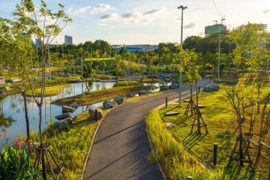 Yeşil ağaçlı yolda asfalt yolda yürü ve kaç. Ofis binası gökyüzü bulutlu.