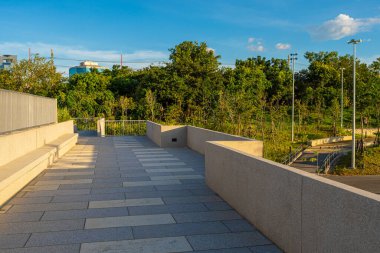 Yeşil ağaçlı yolda asfalt yolda yürü ve kaç. Ofis binası gökyüzü bulutlu.