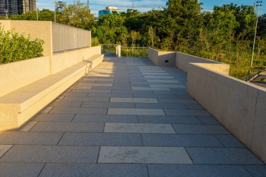 Yeşil ağaçlı yolda asfalt yolda yürü ve kaç. Ofis binası gökyüzü bulutlu.