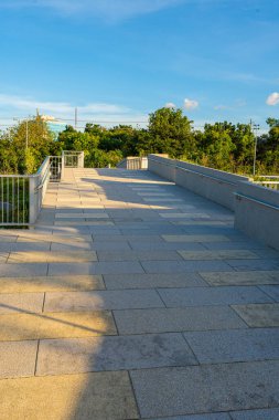 Yeşil ağaçlı yolda asfalt yolda yürü ve kaç. Ofis binası gökyüzü bulutlu.