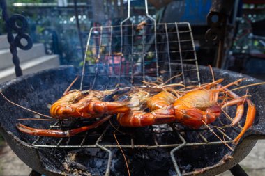 Nehir karidesi ev yapımı dumanlı deniz ürünleri ile ateşte kızartılıyor.