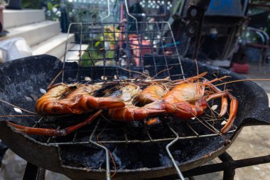 Nehir karidesi ev yapımı dumanlı deniz ürünleri ile ateşte kızartılıyor.