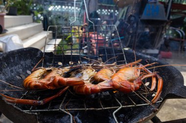 Nehir karidesi ev yapımı dumanlı deniz ürünleri ile ateşte kızartılıyor.