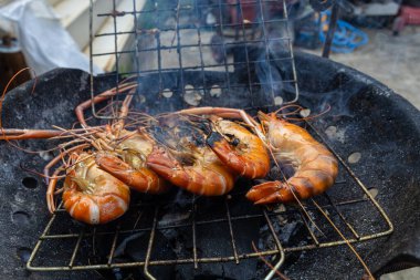 Nehir karidesi ev yapımı dumanlı deniz ürünleri ile ateşte kızartılıyor.