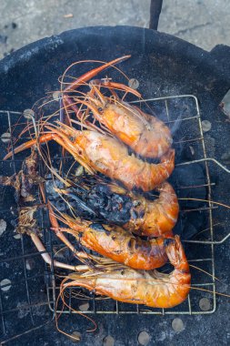 Nehir karidesi ev yapımı dumanlı deniz ürünleri ile ateşte kızartılıyor.