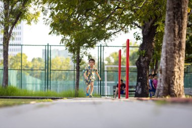 Asyalı çocuk yeşil çayırlarda koşmaktan zevk alıyor.