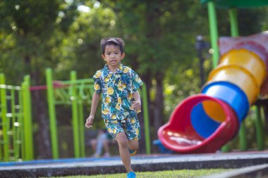 Asyalı çocuk yeşil çayırlarda koşmaktan zevk alıyor.