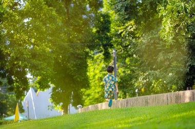Asyalı çocuk yeşil çayırlarda koşmaktan zevk alıyor.
