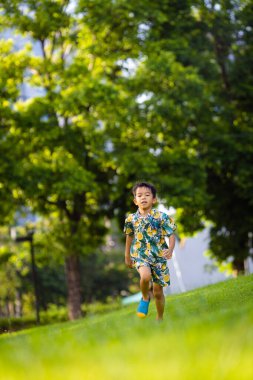 Asyalı çocuk yeşil çayırlarda koşmaktan zevk alıyor.