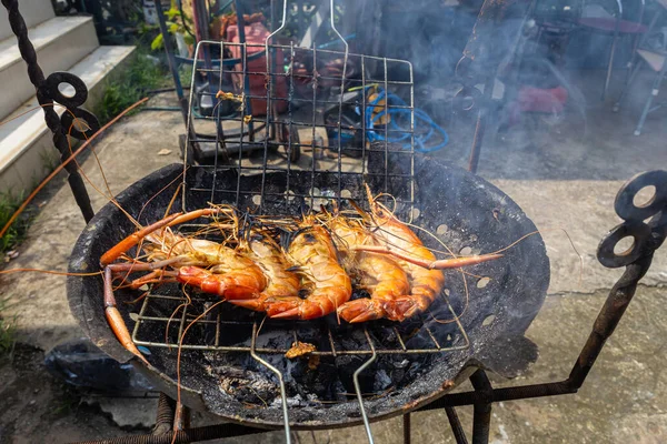 Nehir karidesi ev yapımı dumanlı deniz ürünleri ile ateşte kızartılıyor.