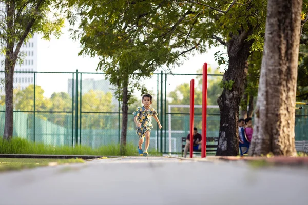 Asyalı çocuk yeşil çayırlarda koşmaktan zevk alıyor.