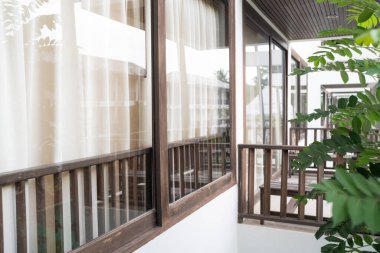 Otel odasındaki kanepeli modern perde toprak tonunda ahşap süslemeli tropikal otel tatil köyü.