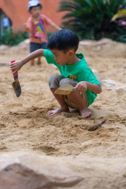 Sevimli küçük anaokulu çocuğu dışarıda kumlu çocuk parkında eğleniyor.